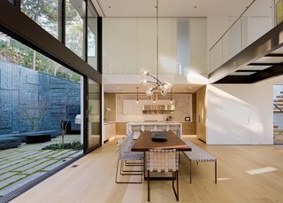 Above the kitchen and dining room, a glass bridge connects bedrooms on the third floor. "The glass flooring allows the southern light to penetrate farther into the space, but also creates a special moment of pause to experience the scale and volume of the space below and towering trees beyond," says Maniscalco.