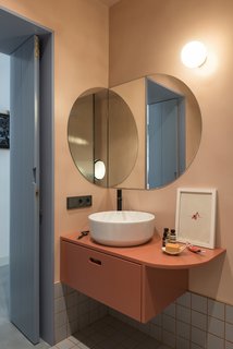 The coral-hued bathroom features a custom vanity designed by CaSA, a Green 42 vessel sink by Catalano, a LEAF faucet by Bruma, and grey ceramic floor tile by Ceramica Vogue.