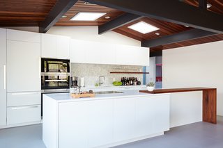 The relocated kitchen is anchored to one side of the home, rendering the rest of the space open and usable. White custom cabinetry and Caesarstone counters keep the room bright and airy. The kitchen appliances are from Miele, with the addition of a Sub-Zero refrigerator and ceiling-mounted Futuro Futuro flush range hood.