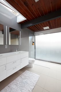 The home’s bathrooms feature Lacava undermount sinks, Hansgrohe fixtures, and Duravit toilets. Natural light filters in through a skylight above the vanity.