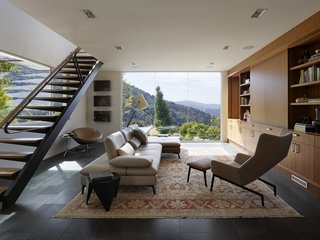50 Modern Homes With Floor-to-Ceiling Windows - Photo 29 of 50 - The original home occupies a prominent hilltop overlooking Silicon Valley and faces into the pristine rolling hills of a nature preserve at the end of the house receiving the new addition. Taking cues from dominant natural elements of the surrounding densely wooded hillside – boulders, bark, and leaves – SaA created a two-story addition with the visual weight needed to anchor the long axis of the extended original house. Against this, the architects balanced steel-framed stair treads and awnings that cantilever from minimal structural supports as if leaves from a slender branch.