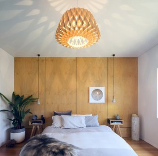 An oversized geometric pendant is expertly matched to the wall behind the bed for a simple, cohesive, and impactful look. 