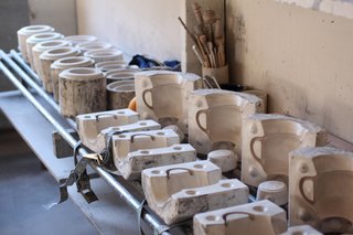 More complicated and hollow forms are made by slipcasting. Liquid clay (called slip) is poured into plaster molds (that we make on-site). The clay dries for 20-30 minutes, the remainder of the liquid clay is poured out and a "wall" of clay that has already dried remains. Considerable work is still needed to finish the piece as the mold leaves lines of clay "flash" on the piece, and a lot of skill is required to make it look as the design was intended to look. 