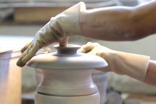 Many details require an addition step. Here, a lid is pulled off the wet clay when it is being formed. This handle is for a casserole lid. There is no mold for this piece, so each finished lid has its own character.