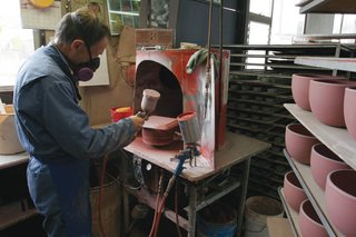 Glaze is applied to the pieces by hand with a spray gun.