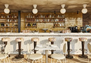 The bar area of Summerly, the rooftop bar and restaurant, displays brass stools upholstered with floral-patterned fabric, geometric tile, and cafe tables and chairs. 