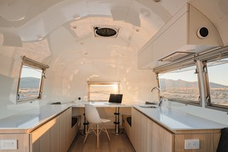 The kitchen and convertible desk area of the Kugelschiff display a luminous, white-painted ceiling and walls, and white ash cabinetry and flooring.