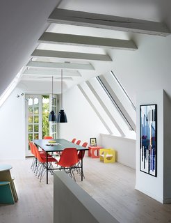 A cramped attic was transformed into a sunny dining room with Vitral windows and white-tinted pine floors by Dinesen. The Sara table is by Hay, the Shell chairs are by Charles and Ray Eames, and the artwork is a hand-printed textile which has been framed.