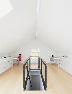 Bamboo flooring and custom built-ins—fashioned from medium-density fiberboard with a white-lacquer finish—brightened the 650-square-foot attic. The custom-designed blackened-steel balustrade has cable inserts and a walnut handrail.