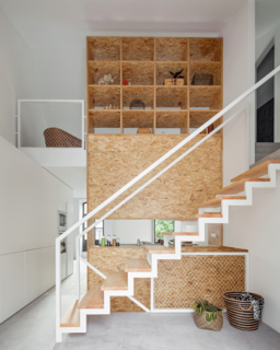 This home reconfigured for an artist in Porto by URBAstudios uses a central unit to create a kitchenette, while also concealing a second-story bedroom from view. 