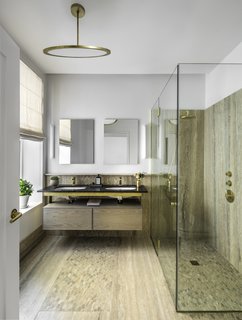 The master bath features a rain shower, Fantini fixtures in natural brass, and accents in travertine and mosaic.