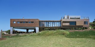 Built from Ipe and exposed concrete, this holiday refuge appears to be emerging from the rocks of its rugged seaside landscape. Located in a fishing village 50 miles north of Punta del Este, on the Atlantic Ocean, the double sloped site of La Roca House is edged by rocks and the remains of the foundation of a pre-existing building which now forms a natural garden of succulents. The home is defined through a sequence of spaces, which consist of two modules of the same height, generating two patios in their voids. The main volume was designed for the social space, and the second for the family's private space—and includes a master bedroom with a stunning panoramic view of the surroundings. 