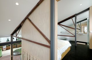 New bedrooms and en suite bathrooms are nestled into the roof volume between the existing<br>trusses by way of plywood-clad pods.