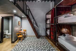 The bunk beds in the communal "Loft Room" are tucked into handcrafted bunks complete with privacy curtains, a lamp, and plug.