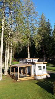 The Flat Roof Caboose design features a loft that can accommodate two beds. Windows give the loft area an open-air feel with an abundance of light. The front of the cabin opens to a private deck. Exteriors are covered with a mix of metal and wood-tone siding for a contemporary finish. 