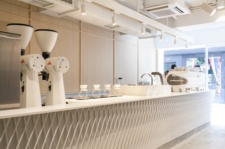 Custom-made by Studio Adjective, the 23-foot-long coffee bar is topped with a white Corian counter. 
