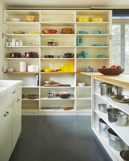 The kitchen's open shelving serves as a colorful display for midcentury-modern cookware. 