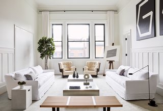 The pale pink armchairs feature a quirky design and add a subtle pop of color in an otherwise white interior. 