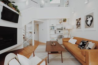 The airy living room features high ceilings and a cozy fireplace. 