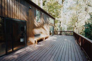 The double-height living room opens to a spacious outdoor deck nestled in the forested "backyard." 