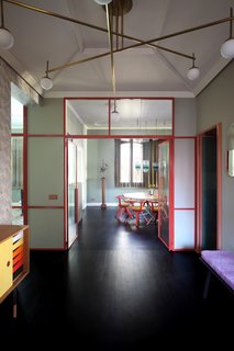 The apartment's entrance is lined with "Vanessa" wallpaper by Mini Moderns. The space features a Finn Juhl sideboard in teak, a chandelier in brass and glass by Commute Design, an Obei Obei mirror by Atipico, and vintage 1950s ceramics from Arts & Crafts Gallery in Venice. There's also a Bench One by Another Country that's been covered in Pillar fabric by Kvadrat.