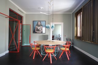 The eclectic dining room houses a LC15 table by Le Corbusier for Cassina, Rival Chairs by Konstantin Grcic for Artek with Kvadrat fabric, a bar cart by Rossana Orlandi, and Flow pendant lights by Wonder Glass. The windows are covered with curtain fabric from Black Edition, along with brass frames by Marcante-Testa that were built by Om Project. 