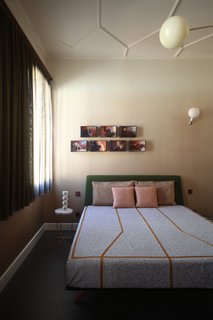 The master bedroom is complete with a Hepburn bed by Matthew Hilton for De La Espada with Kvadrat fabric upholstery, bedcovers made with Rubelli "terrazzo" fabric, an Oliver Tray Side Table by Evie Group, Modo pendant lighting by Roll & Hill, Parola wall lamps by FontanaArte, and a table lamp by Parachilna. 