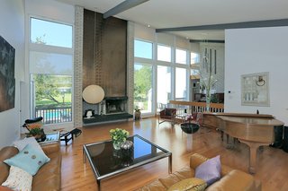 The space is centered by a wood-burning fireplace highlighted by metallic glazed tiles and has a strong midcentury-vibe. A step up from the living room leads to a platform area with an organ. The space boasts beautiful hardwood floors throughout. 
