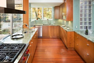 The kitchen features high-end appliances and cabinets elegantly paired with green marble countertops and tiling. 