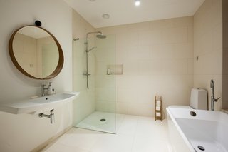 The minimalist bathroom design features an open shower and a freestanding tub. 