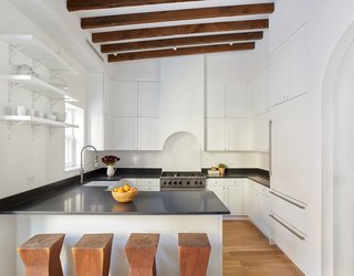 These 30 White Kitchens Are Anything But Ordinary - Photo 4 of 30 - A crisp, clean, eat-in kitchen with high-end appliances from Viking, Bosch, Sub-Zero, and LG make this space a chef's delight, while exposed beams, an arched stove hood, and a second arched carriage entrance along the back wall connect the room to the home’s rich past.