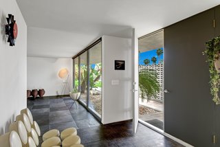 The entry hall has natural lighting thanks to floor-to-ceiling windows, yet offers privacy due to an exterior wall. 