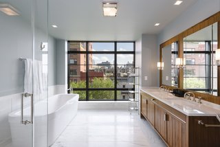 The luxurious master bath has a double vanity, soaking tub, glass-enclosed stall shower, and a wall of windows.