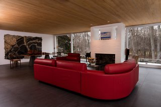 The living room features cypress ceilings, an open brick fireplace, and expansive glazing. 