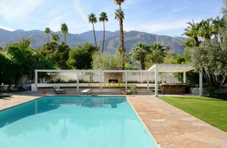 A Luminous Palm Springs Midcentury Asks $3.35M - Photo 12 of 16 - The outdoor entertaining space includes a shuffleboard court and a built-in outdoor seating area complete with a fireplace and barbecue. 