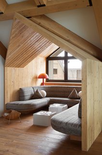 A second spruce alcove frames a nook with wool-covered custom seating, and features Nendo’s Innerblow coffee tables with blown molten-glass tops; the geometric pillows were designed by Pierre Yovanovitch.