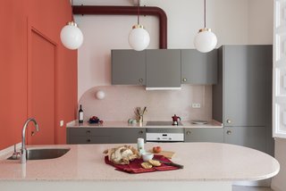 Three globe pendants with brass details and burgundy cords that match the hood tube hang above the kitchen island. 