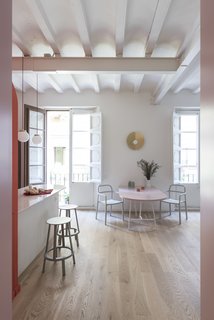 Between the two big windows, the golden "Fold Lamp" presides over the dining area, which consists of a wide pink lacquered table. The Ypperlig chairs pictured above are by HAY for IKEA.
