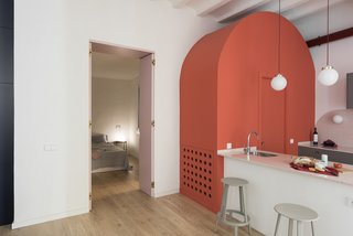 An arc-shaped, coral-colored volume that hides a powder room has become a main feature of the design.