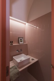 The guest bathroom sits hidden in a coral-colored volume off the kitchen. 
