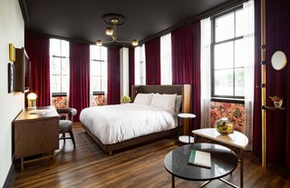 The dark velvet floor-to-ceiling curtains paired against the bronze lighting and wooden floors define the vintage vibe in the guest rooms. 