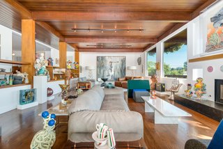 The bright and airy living room is a visual study of vertical and horizontal forms and features a stunning redwood ceiling.