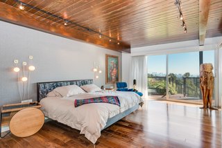 The master bedroom on the upper level features hardwood floors and redwood ceilings, and opens to a terrace. 