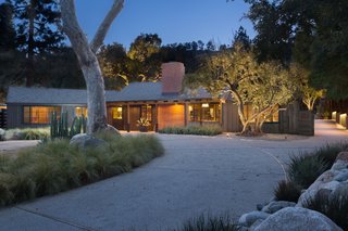 The outdoors are easily accessed from every room, showcasing a mix of large specimen trees, drought tolerant plants, and decomposed granite and river rock.