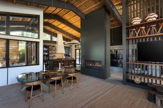 The interior of the main home is elegant and airy, with a dark palette warmed by the use of natural wood. A dramatic fireplace is the centerpiece of the open-plan great room. 