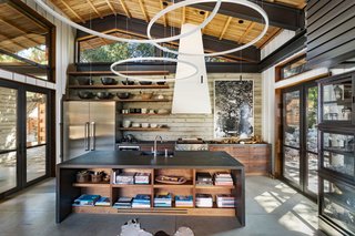 The chef's kitchen features custom crafted cabinetry, a commercial size pantry, and an epic island of mallet stamped stone. It also benefits from ample glazing, which helps the space bring in an abundance of natural light. 