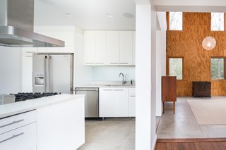 An Eco-Friendly Connecticut Home Wants $650K - Photo 6 of 10 - The double-height living area features unfinished plywood cladding. The sleek, contemporary kitchen features a center island, as well as stainless steel appliances.