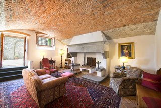 You Can Own Michelangelo’s Former Tuscan Villa For $9.3M - Photo 4 of 11 - The living room features a brick vaulted ceiling and a stone fireplace with seating nooks.