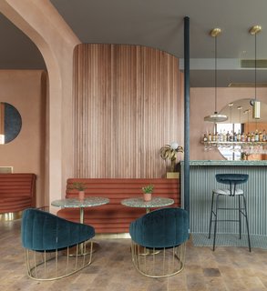 A Historic London Property Is Converted Into a Modern Mediterranean Eatery - Photo 5 of 8 - Scalloped Sapele wood slats on the walls add a textural organic element. The gorgeous brass and velvet Tonello armchairs are from Note Design Studio, and the end-grain wood flooring is from Havwoods. 