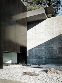 This Concrete Abode Stretches Over Giant Boulders - Photo 4 of 17 - The exterior features a poetic layering of spaces that highlights the interplay of light and dark. 